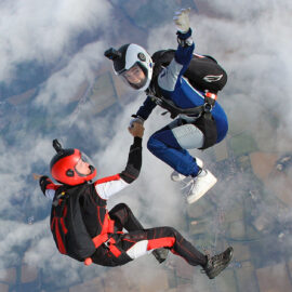 Two skydivers hold hands in freefall