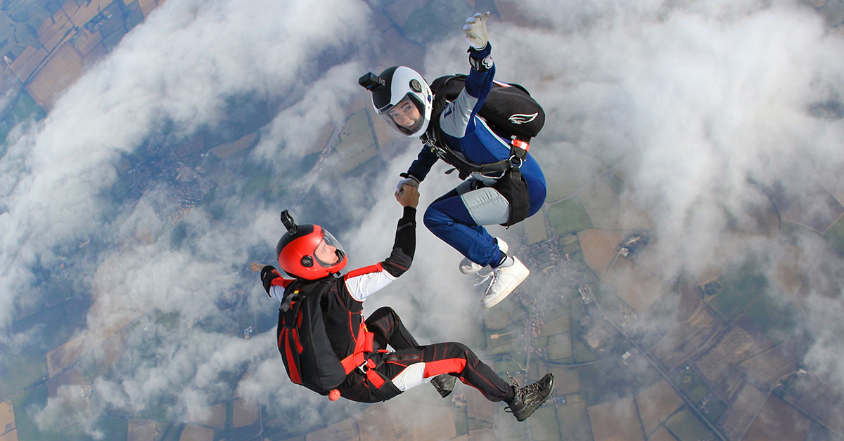 Two skydivers hold hands in freefall