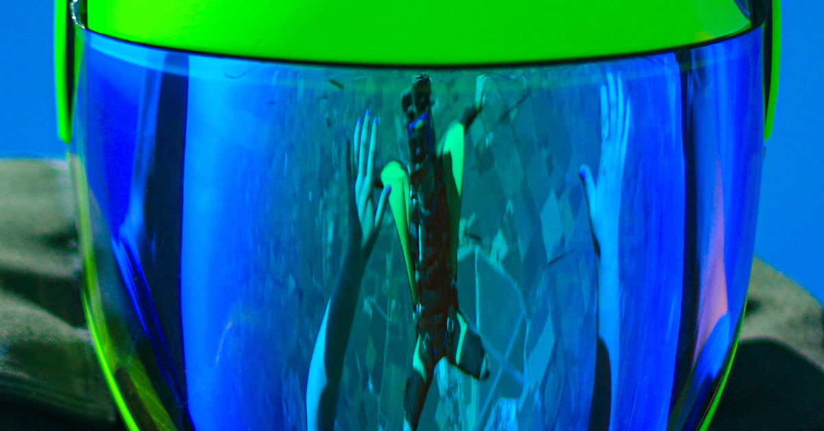 Reflection of a wingsuiter in the helmet of a skydiver