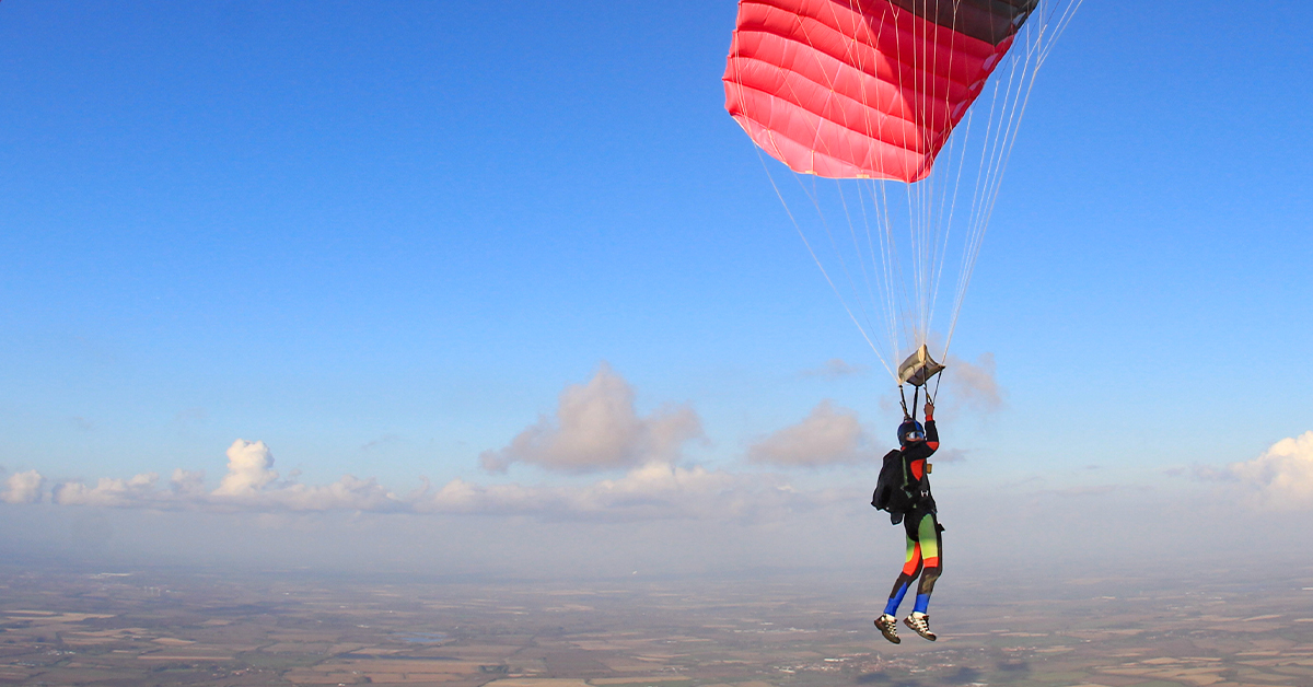 Skydiving gliding through the clouds with their parachute open