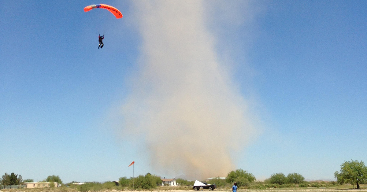 Dust gathers in the winds over the desert, as a skydiver navigates the swirling hazard