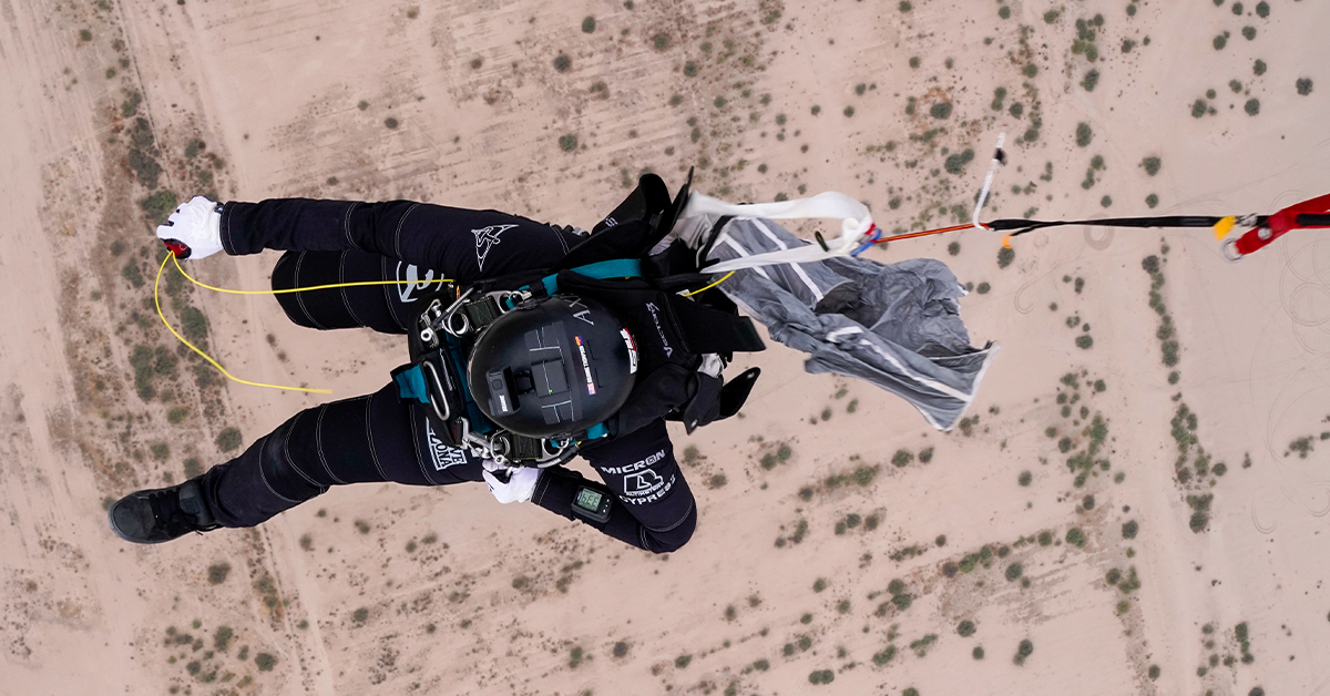 A skydiver looks down on the desert