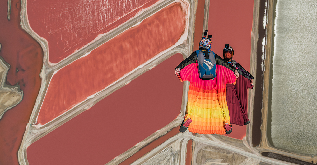 Two wingsuiters face to face over the red fields of Namibia.